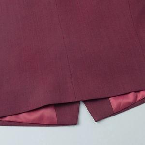 Detail of dark burgundy suit vest hem showing fine twill fabric and pink silk lining