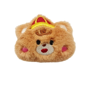 Cute brown plush tiger brooch with embroidery details and crown on white background