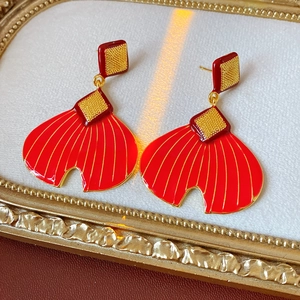 Detail von rot-goldenen Fischschwanz-Ohrringen mit Emaille-Finish auf einem Tablett