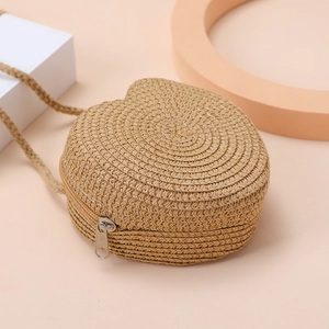 Detail of heart-shaped woven straw bag with zipper and woven shoulder strap