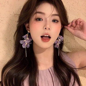 Détail de boucles d'oreilles fleur violette à pompons avec chaînes élégantes