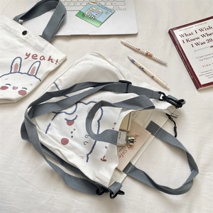 Detalle de bolsos de lona blanca con estampados de animales y correas grises ajustables