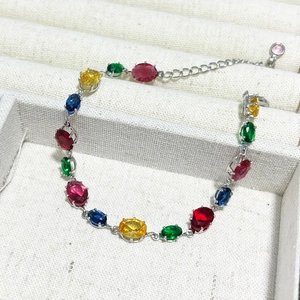 Detail of colorful oval gemstone bracelet with silver claw settings on jewelry tray