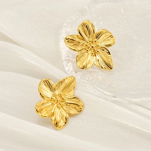 Elegante goldene Blumenohrstecker mit strukturierten Blütenblättern auf Seidenhintergrund