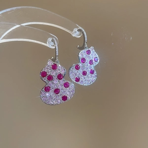 Detail of silver gourd earrings with pink and red zircons on a clear stand
