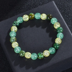 Elastic beaded bracelet with green and yellow natural stones on a black jewelry box