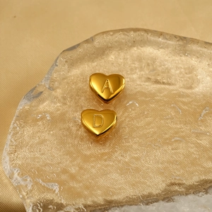 Golden titanium steel heart charms with engraved A and D letters on elegant silk background