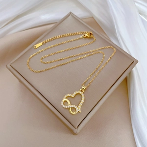 Macro detail of a golden infinity heart pendant with sparkling white zircons on a fine chain