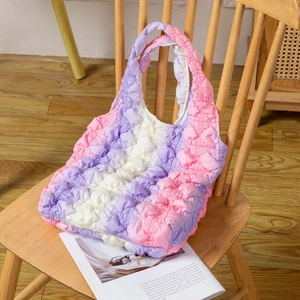 Sac fourre-tout matelassé à texture bulles et dégradé pastel posé sur une chaise en bois