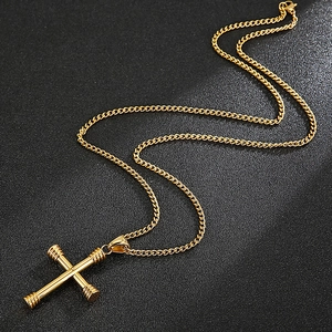 Close-up of vacuum plated gold cross pendant necklace with metallic chain on black texture