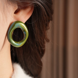 Detailed view of vintage green iridescent glass hoop earrings on a model