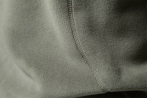 Macro detail of high-density army green polar fleece fabric with premium stitching
