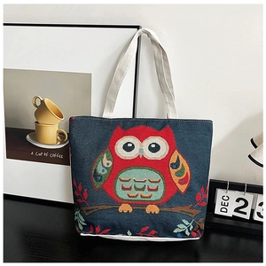 Detail of canvas tote bag featuring an embroidered red owl pattern and cotton handles