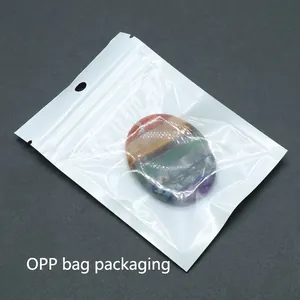 Oval chakra healing stone with colorful stripes in transparent packaging on dark background
