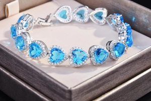 Close-up of heart-shaped blue sapphire bracelet with halo diamonds in a gift box