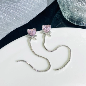 Detail of pink heart crystal earrings with silver bow and long metal tassels