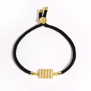 Detail of adjustable black silk cord bracelet with micro-paved cubic zirconia gold charm