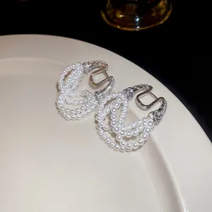 Elegant multi-layer pearl tassel earrings with zircon horseshoe buckle on white plate