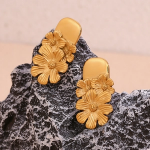 Macro shot of 18K gold plated stainless steel floral earrings on a dark rock