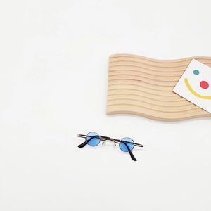 Detailed close-up of mini round blue lens sunglasses with a gold metal frame on wood