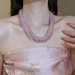 Detail of multi-strand pink beaded necklace with layered texture on a female model