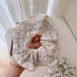Macro shot of large cotton scrunchie with grey vintage lace floral pattern on cream fabric