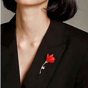 Detailed view of red tulip brooch with pavé diamonds and a round white pearl on black fabric