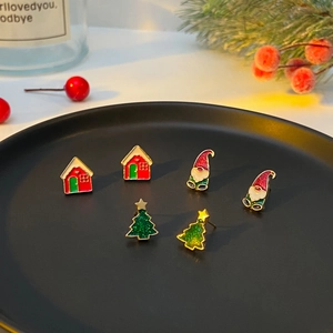 Macro shot of Christmas earring set with Santa Claus, snowy house, and green tree