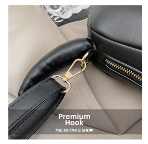 Macro view of gold metal hooks and black leather shoulder strap on a commute bag