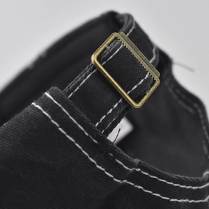 Detail of black cotton twill baseball cap with vintage bronze buckle and contrast stitching