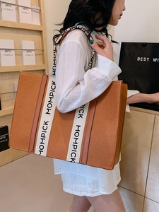 Brown felt tote bag with white lettered straps shown on model for a stylish casual look