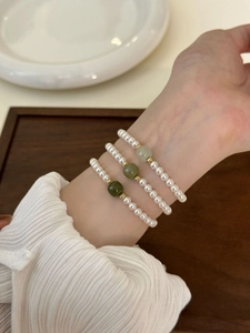Close-up of pearl and green jade beaded bracelets styled on a woman's wrist