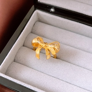 Detail of 18K gold plated bow ring with fine texture and diamonds in a jewelry box