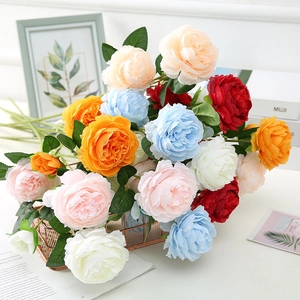 Detailed close-up of colorful artificial peony flowers in a rose gold metal mesh basket