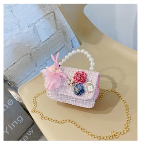 Detail of pink tweed girl crossbody bag with pearl handle and cartoon rabbit charm