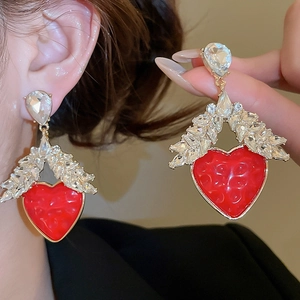 Détail macro de boucles d'oreilles cœur en résine rouge et cristaux brillants