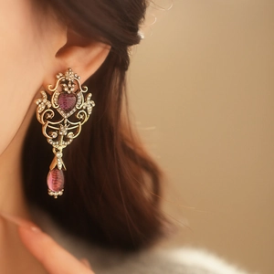 Detail of vintage Baroque earrings with purple heart crystals and gold finish on model
