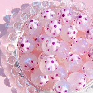Gros plan de perles en résine lumineuses 16mm avec motifs floraux roses pour bijoux artisanaux