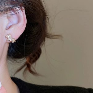 Close-up of gold-plated unicorn earrings with small diamonds on a model