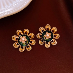 Detailed macro view of vintage gold flower earrings with green enamel and pearl inlay