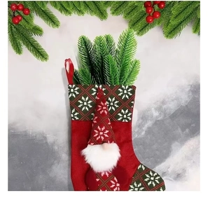 Red Christmas stocking with plush gnome detail and artificial green pine branch decor