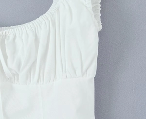 Detailed view of white dress with ruched bodice and ruffled shoulder strap design
