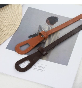 Close-up of caramel and dark brown thin belts with silver rivets on a lifestyle background
