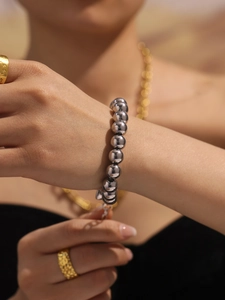 Detailed close-up of polished silver beaded bracelet on wrist with elegant gold jewelry