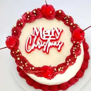 Acrylic Merry Christmas cake topper on white frosted cake with red cherries and gold pearls