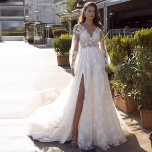 White lace V-neck wedding dress with long sleeves, high slit, and an elegant long train