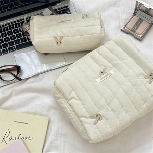 Detailed macro of cream quilted cotton storage bags featuring cute rabbit embroidery
