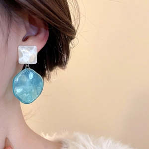 Close-up of elegant double-layer drop earrings with blue resin on a model in profile
