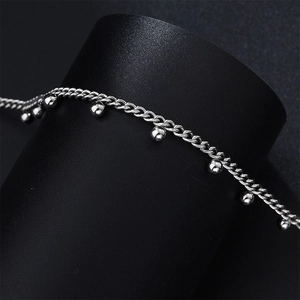 Close-up of silver steel chain necklace with ball pendants on a black display stand