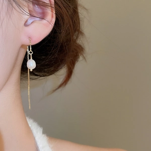 Detail of long gold tassel earrings with elegant freshwater pearls on a model